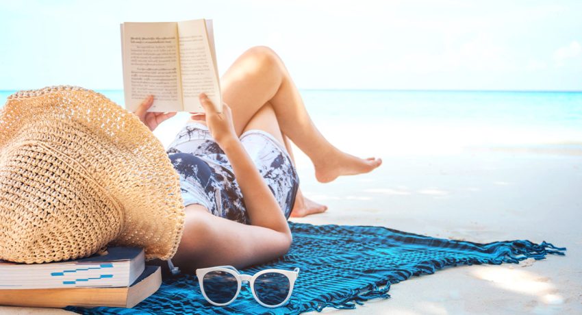 girl reading a book on the beach